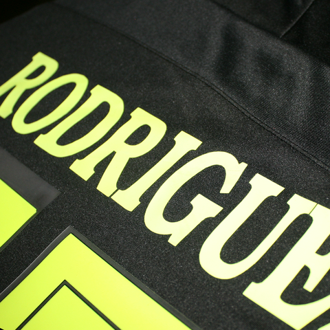 Vinyl neon green iron on name attached to a black soccer jersey